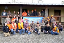 Large group of hunters gathered in front of a lodge holding the Pheasants Forever Yolo County banner at the 2020 R3 Upland Bird Hunt