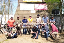 Large group of veterans and chapter members kneeling and standing in front of a barn displaying their pheasant harvest at the 2022 Veterans Upland Bird Hunt
