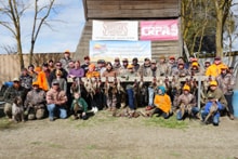 Large group of hunters and participants posing in front of the event barn with Pheasants Forever Yolo County, Shooter's Pro Shop, and CRPA sponsor banners at the 2024 R3 Upland Bird Hunt