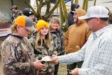 Adult man in a white shirt posing with two young hunters in camo and a teenage girl in camo at the 2024 R3 Upland Bird Hunt