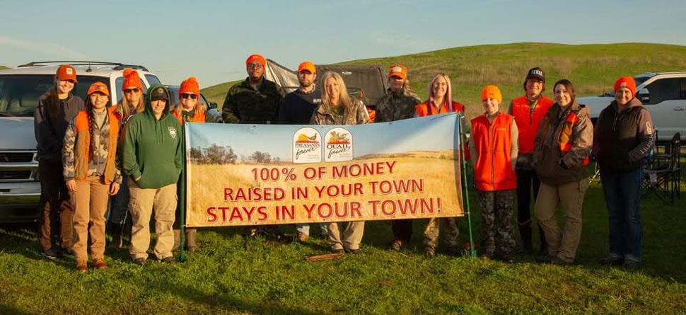 Group of hunters holding a Pheasants Forever banner in a field