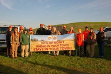 Small group of hunters holding a Pheasants Forever banner in a field