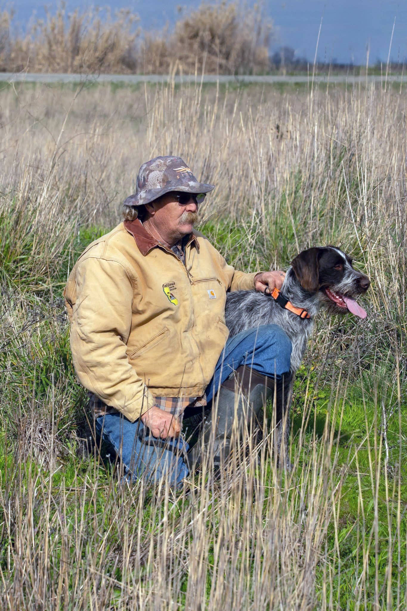 Mentor with a hunting dog working through a wetland marsh at the 2025 Youth Mentor Hunt