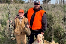 Two mentors in blaze orange vests and camo at the 2025 Youth Mentor Hunt
